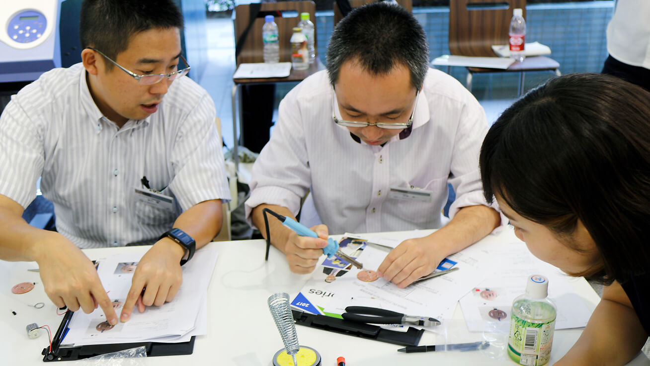 Participant with soldering skills giving others helpful tips.