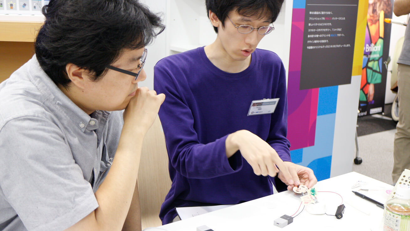 Team members discuss how to arrange circuit boards to create an interesting design.