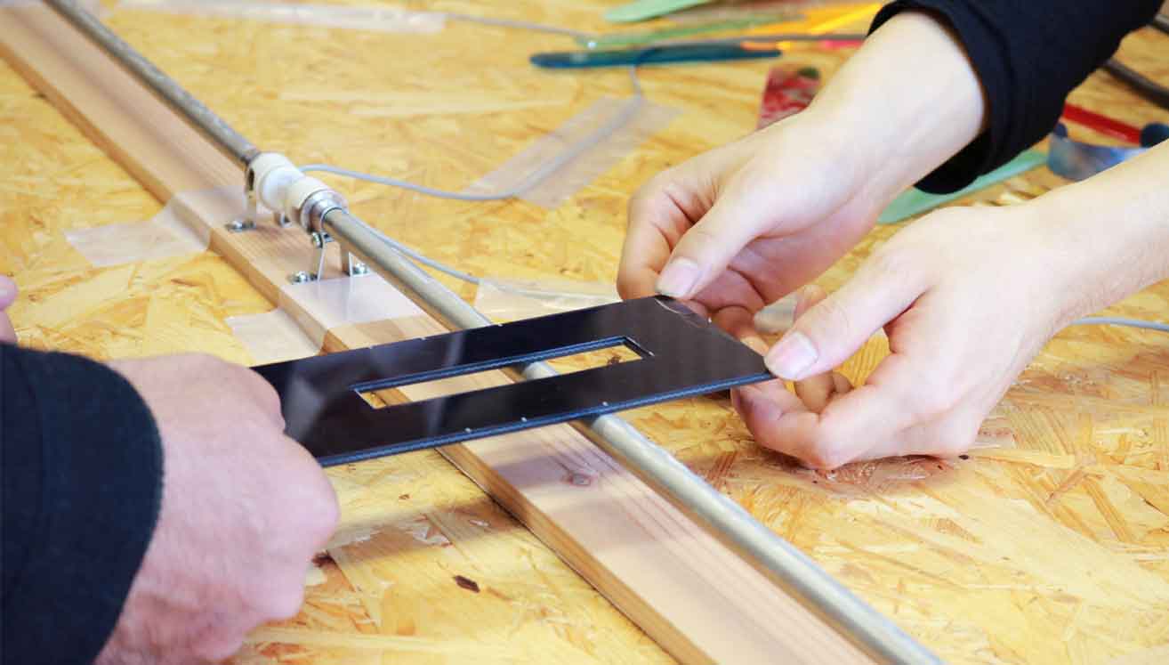 Heating up acrylic by holding it close to a heater, and then bending it into shape to form a stand.