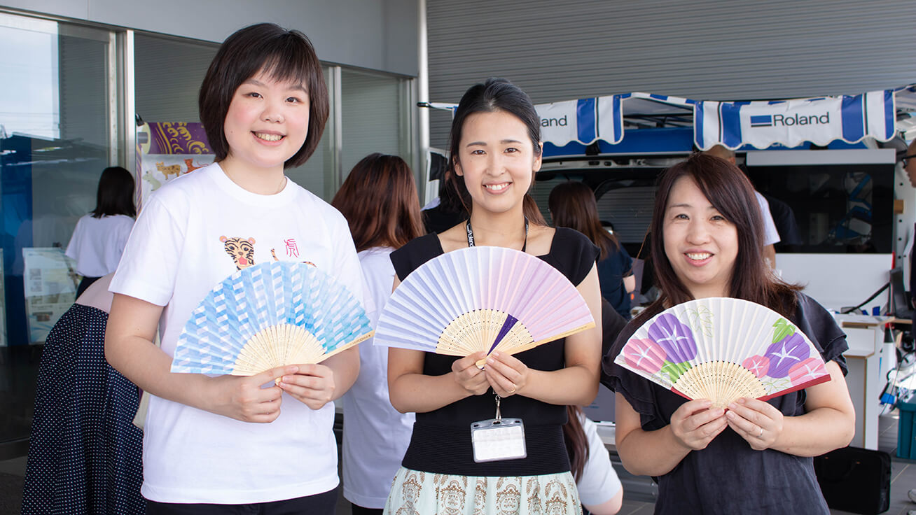 Employees proudly display their personalized folding fans with Meng.