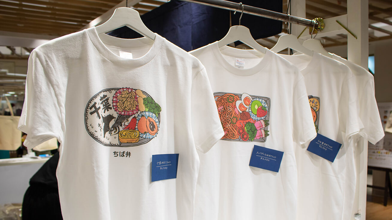 Exclusive event-only T-shirts with Chiba-themed lunchbox designs featuring local produce like peanuts (left).