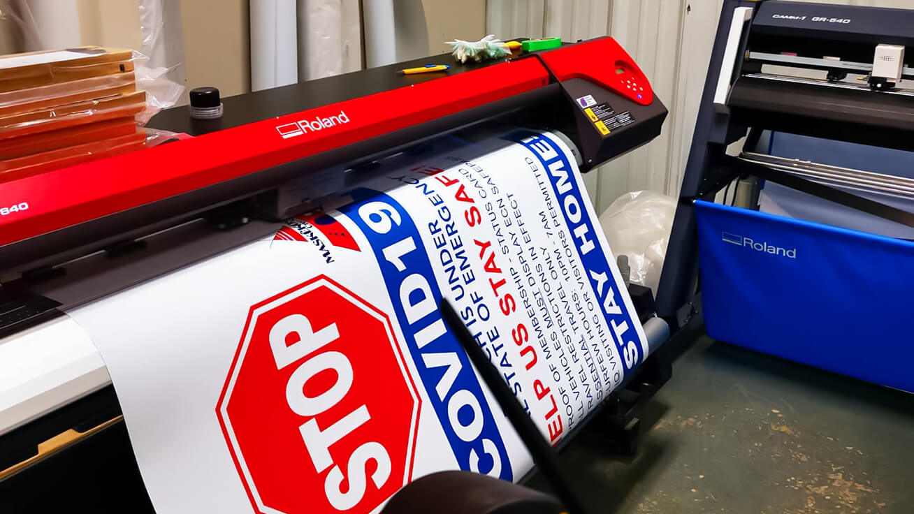 Large-format signs being printed on a Roland DG VersaEXPRESS RF-640 8-Color and cut with a CAMM-1 GR-640 cutter at Printology Digital for local Alberta businesses.