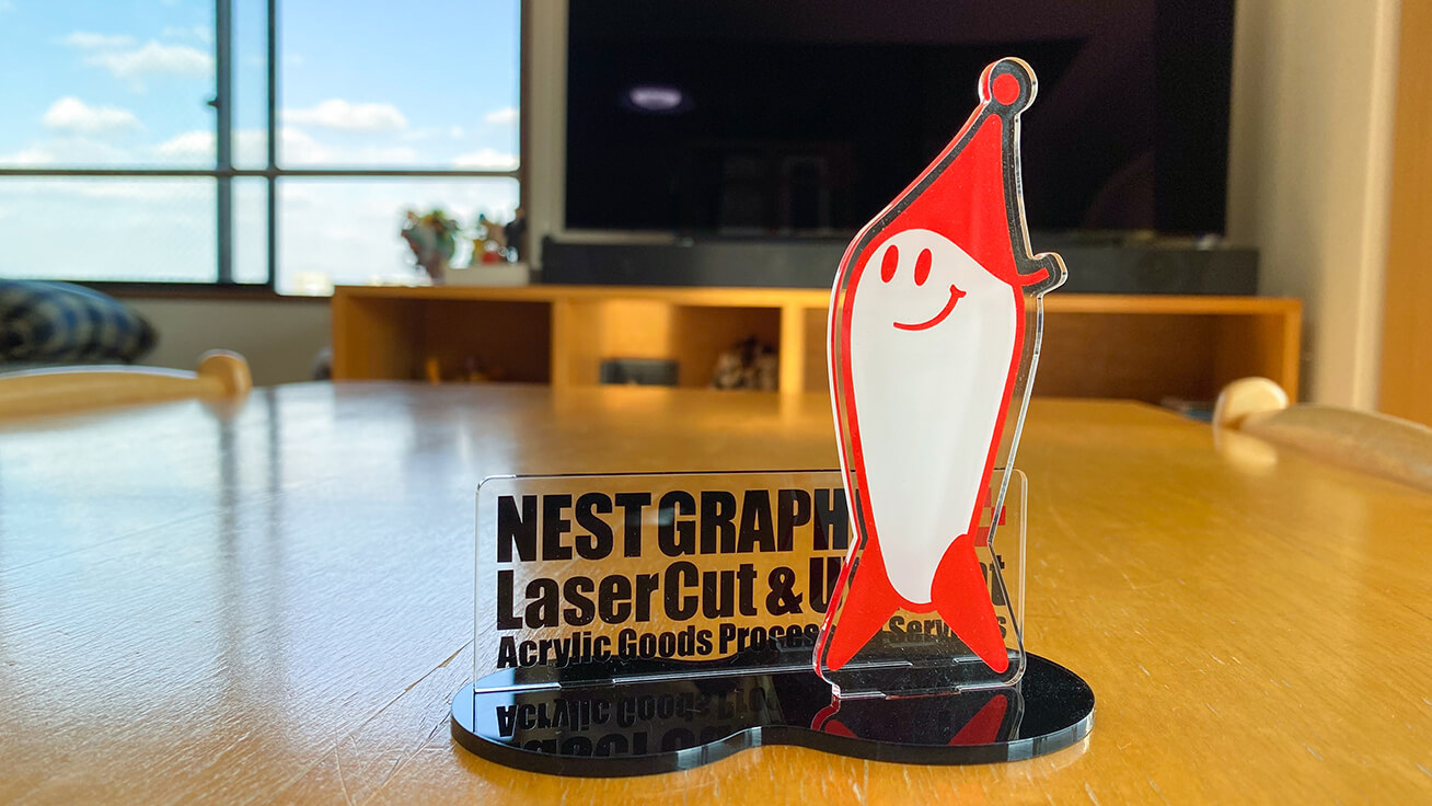 This acrylic stand features the NEST GRAPHICS character mascot.