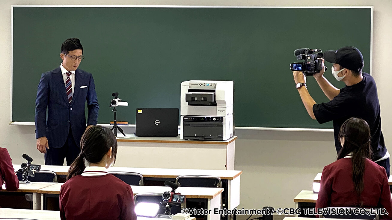 The BT-12 direct-to-garment printer on the set at the recording studio. CBC TELEVISION anchor Keiichi Wakasa is on the left as the show host.