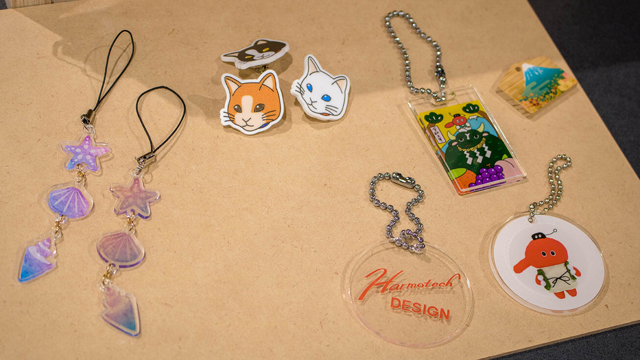 A member’s original mascot featuring a long-nosed goblin in Japanese folk religion (right), and a staff member’s drawings made into keychains and pins (left)